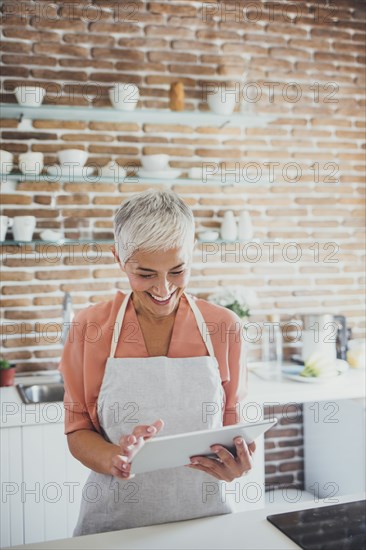 Older Caucasian woman using digital tablet in kitchen