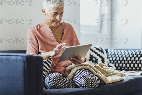 Older Caucasian woman using digital tablet on sofa