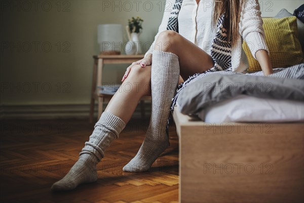 Caucasian woman sitting on bed wearing socks