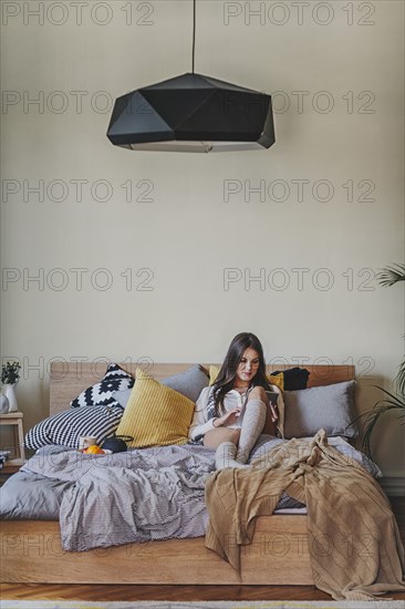 Woman reading digital tablet on bed