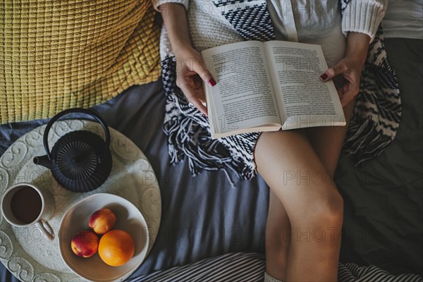 Woman reading book on bed