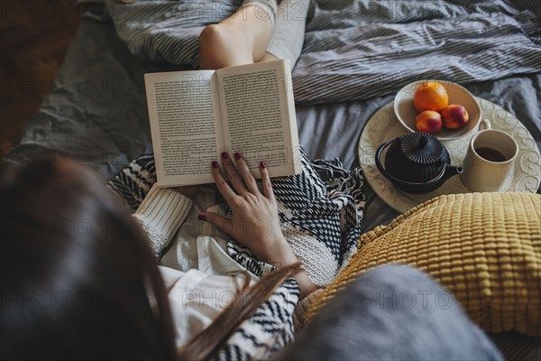 Woman reading book on bed