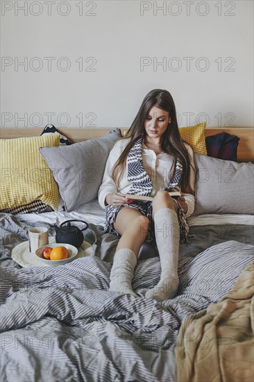 Woman reading book on bed