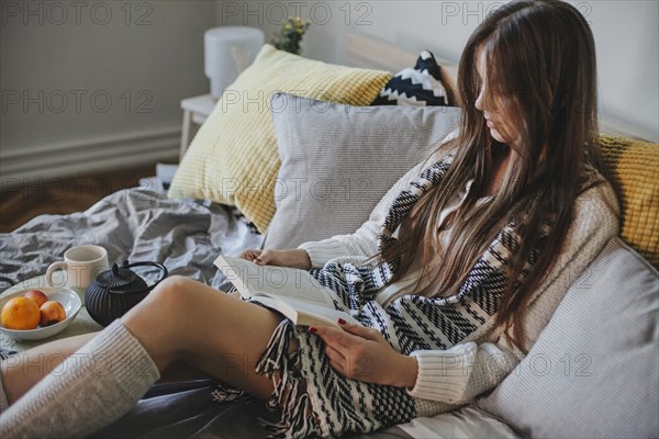 Woman reading book on bed