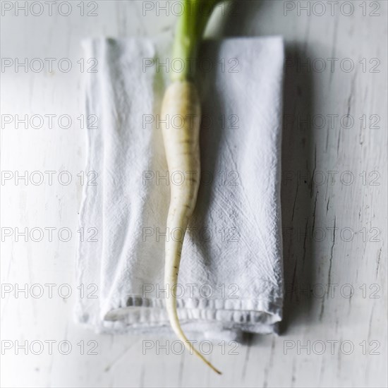 White carrot on napkin on white wooden table
