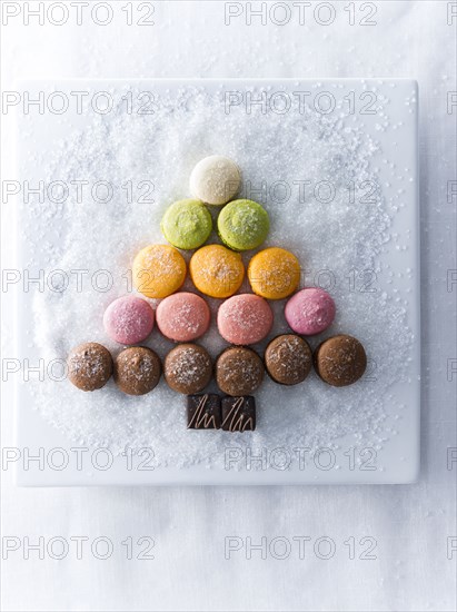 Macaroons and chocolate in shape of tree on plate with sugar