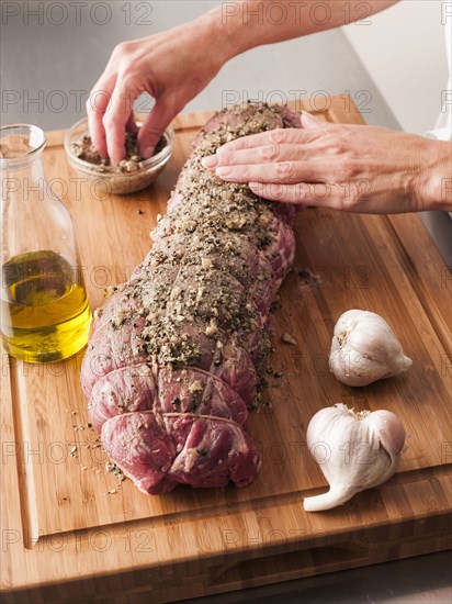 Hands rubbing garlic and pepper onto tenderloin