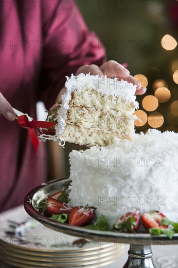 Hands serving slice of coconut cake