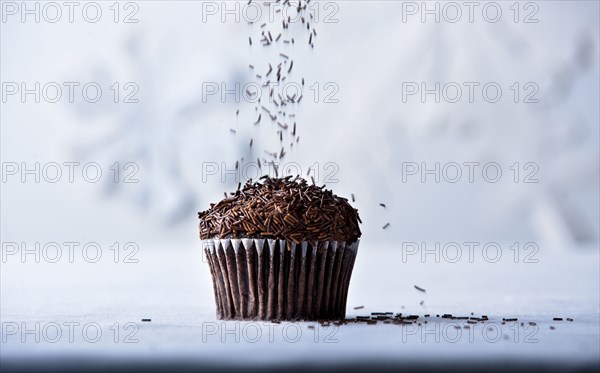 Brown sprinkles falling on chocolate cupcake