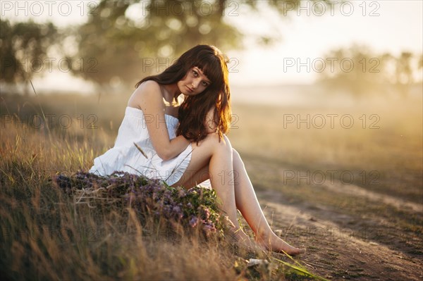 Caucasian woman sitting in rural field