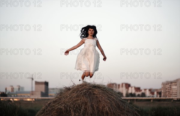 Caucasian woman jumping on haystack