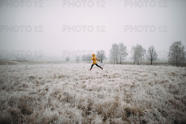 Caucasian woman leaping in snowy field