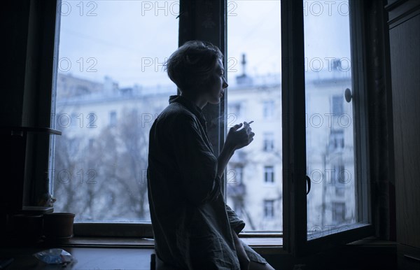 Caucasian woman smoking at open window