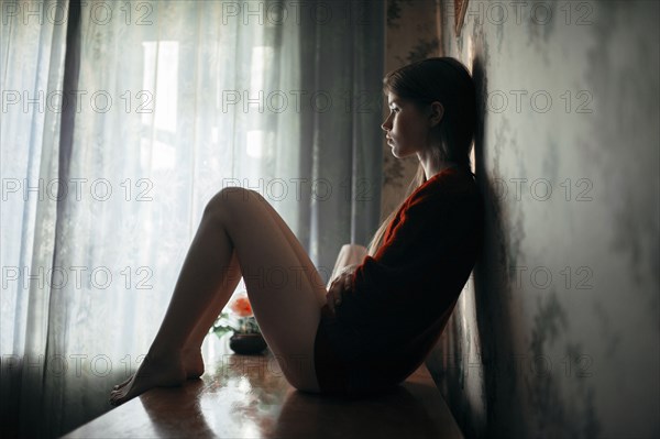 Caucasian woman sitting on credenza indoors