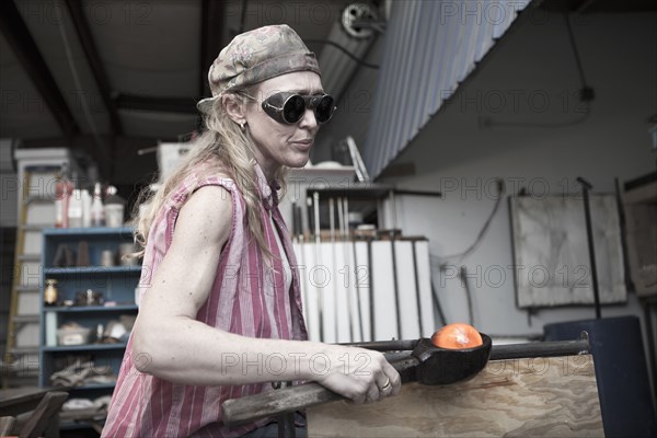 Caucasian woman in glass blowing studio