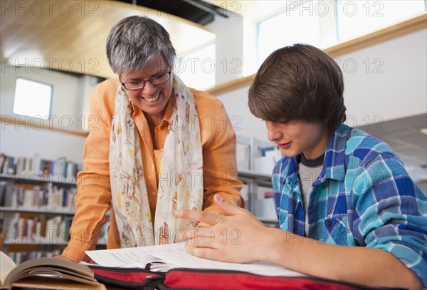 Librarian helping boy with homework in library