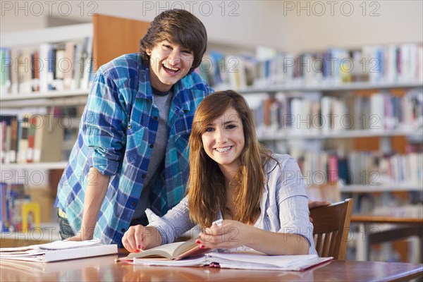 Smiling students doing homework in library