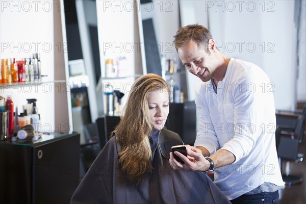 Hairdresser showing cell phone to client