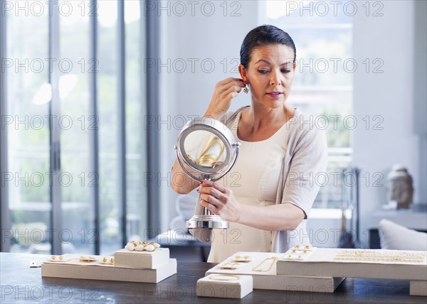 Hispanic woman trying on earrings in jewelry store