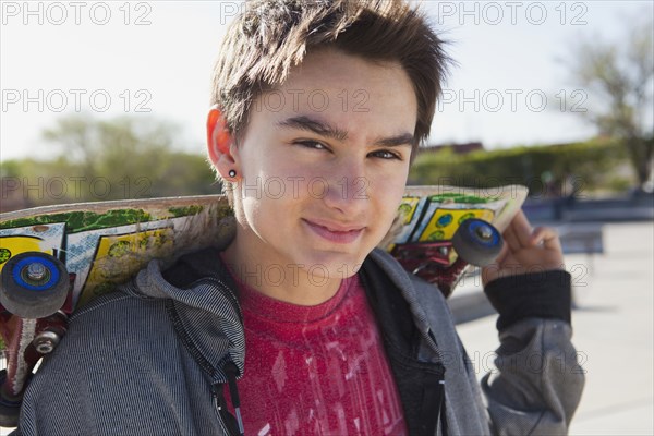 Smiling mixed race boy holding skateboard