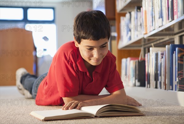 Hispanic boy reading book in library