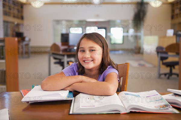 Smiling mixed race girl studying in library
