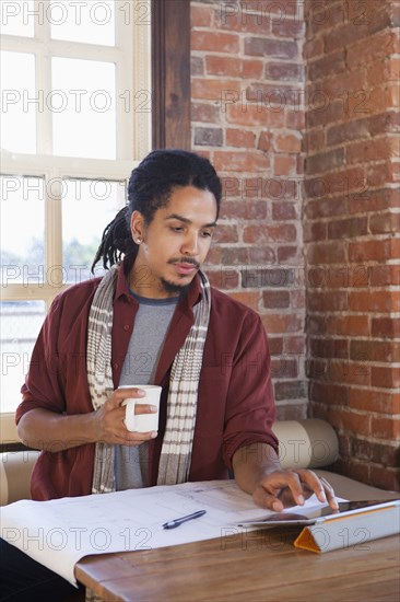 Mixed race man using digital tablet in coffee shop