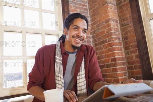 Mixed race man using digital tablet in coffee shop