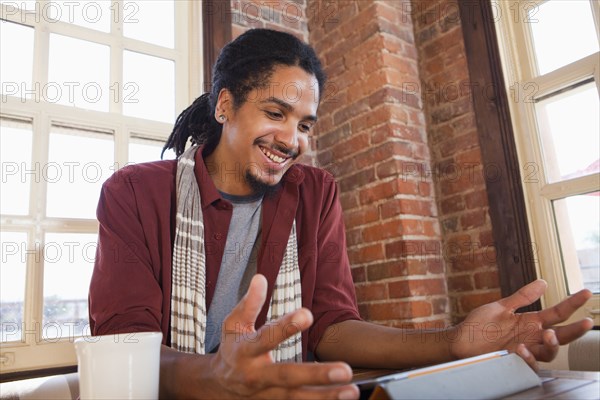 Mixed race man using digital tablet in coffee shop