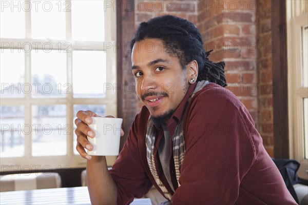 Mixed race man drinking coffee in coffee shop