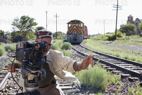 African American man with film camera near railroad tracks