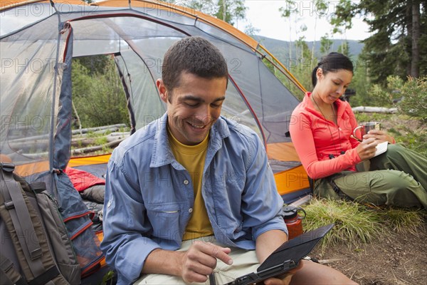 Man using digital tablet while camping