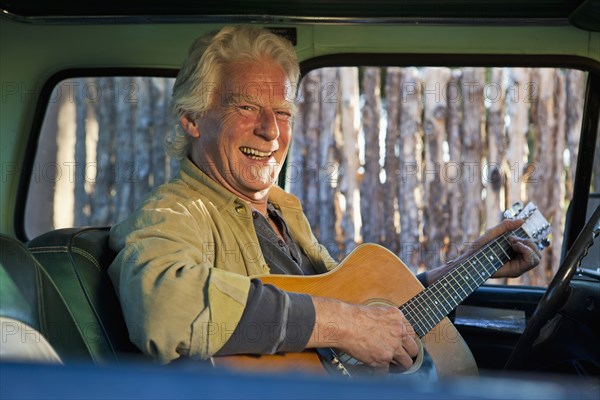 Caucasian man playing guitar in truck