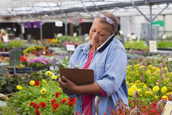 Mixed race woman talking on telephone in plant nursery