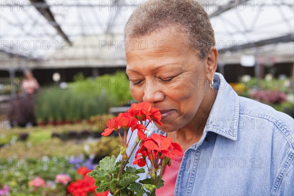 Mixed race woman smelling flower in plant nursery