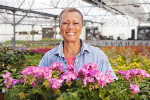 Mixed race woman standing with flowers in plant nursery