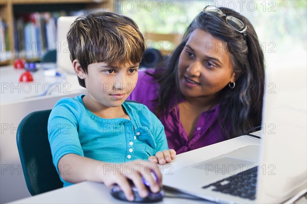 Teacher helping student using laptop