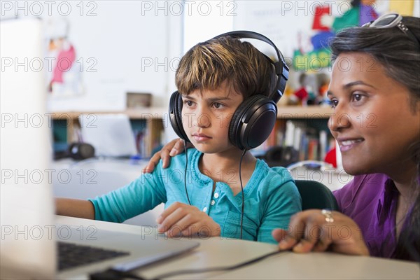 Teacher helping student using laptop