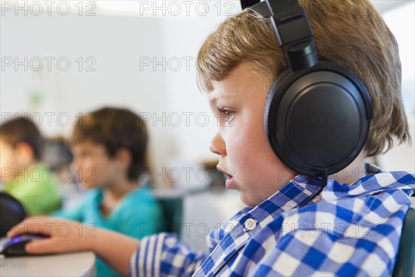 Caucasian student listening to headphones in classroom