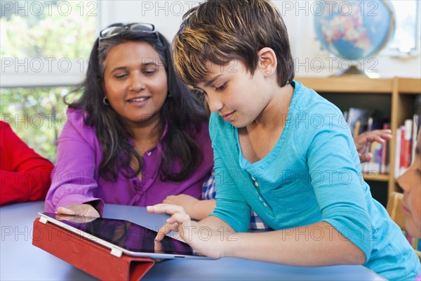 Teacher and student using digital tablet in classroom