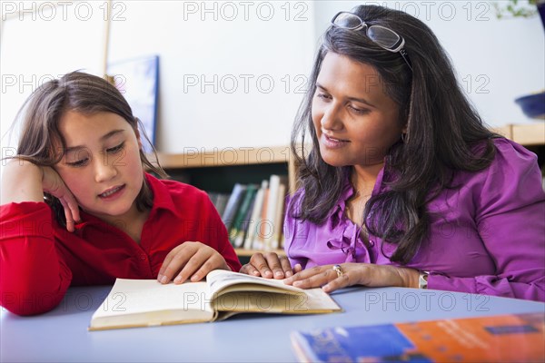 Teacher and student reading book in classroom