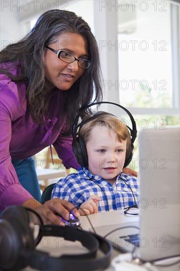 Teacher helping student using laptop in classroom