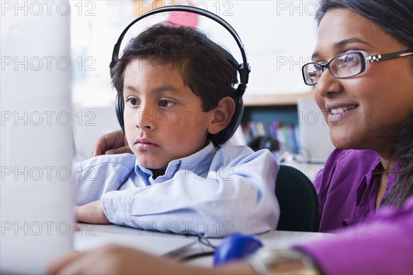 Teacher helping student using laptop in classroom