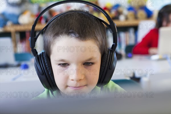 Caucasian student in headphones using laptop in classroom