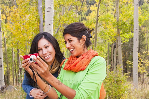 Friends looking at digital camera in forest