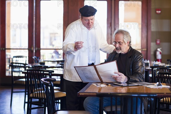 Caucasian man talking to chef in restaurant