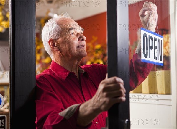 Caucasian florist hanging open sign in shop