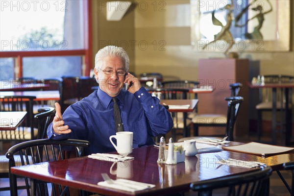 Hispanic cafe owner talking on cell phone