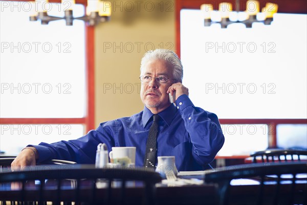 Hispanic cafe owner talking on cell phone