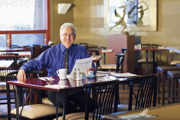 Hispanic cafe owner sitting at table